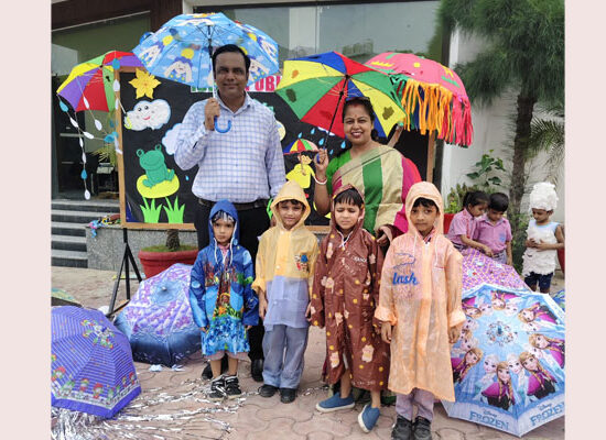 Kindergarten students of Ideal Public School Agwanpur celebrating Rainy Day in colourful raincoats and umbrellas.